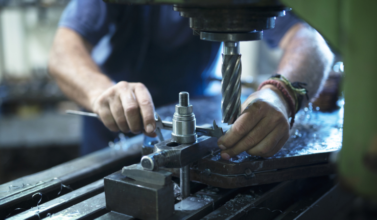 Worker operating industrial machine in metal workshop.